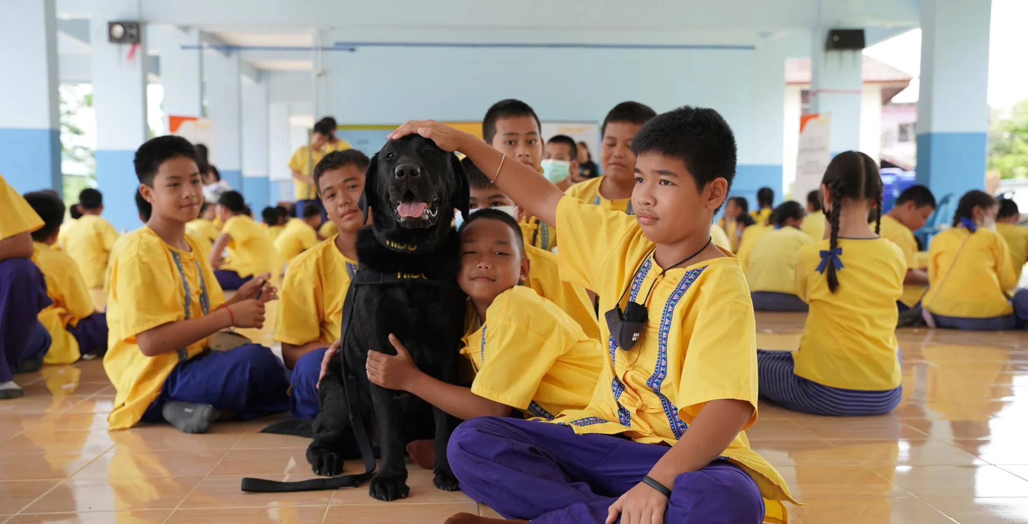 A group of young kids hug and pet a K9 named Hidu