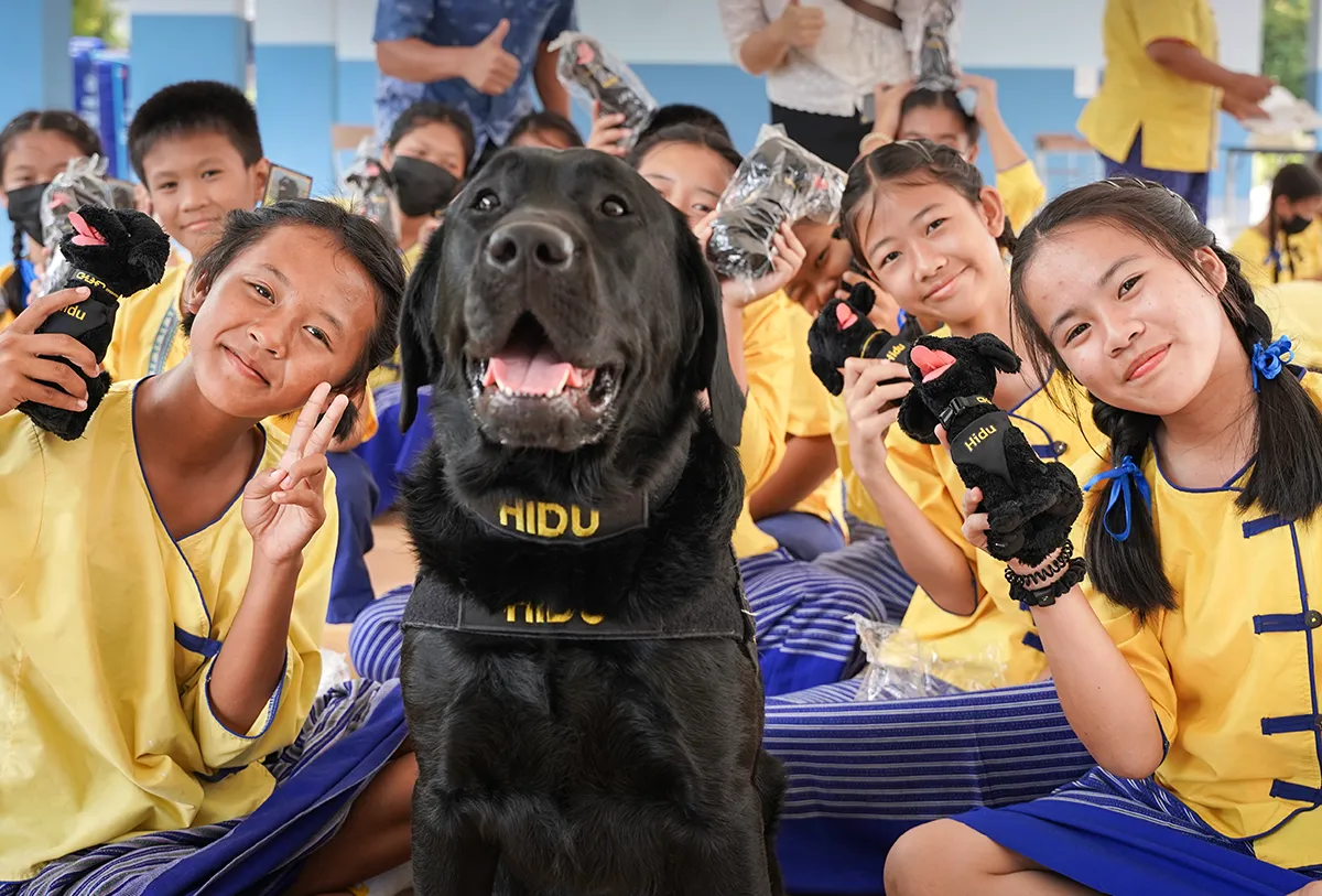 Kids smiling next to a K9 named Hidu